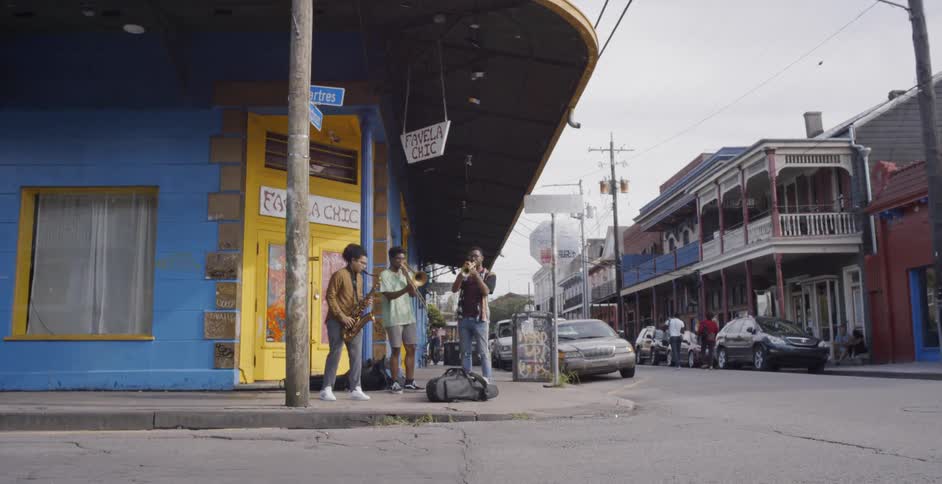 Three black boy play saxophone before the yellow door in the street on a cloudy day
