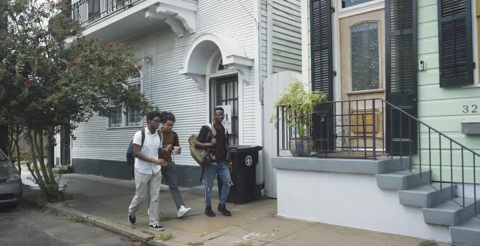 Three teenagers walk down a sidewalk together