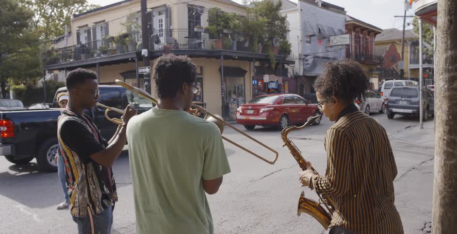 Three people in a street corner playing instruments