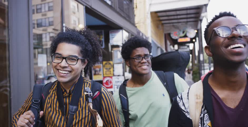 Three black men walk down the street laughing