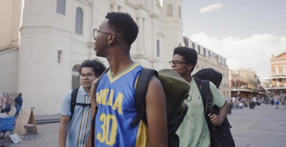 Three black men walk across a plaza in the city