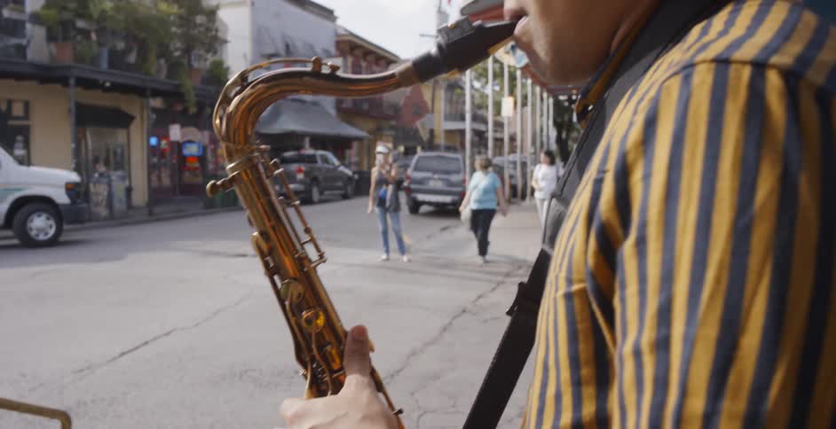 Musicians play instruments on the street as cars and pedestrians pass by