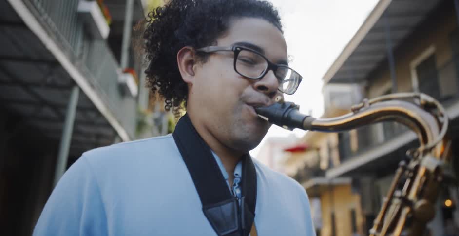A black male playing a brass musical instrument on the street