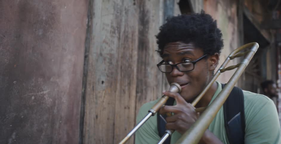Man plays trombone near business entrance