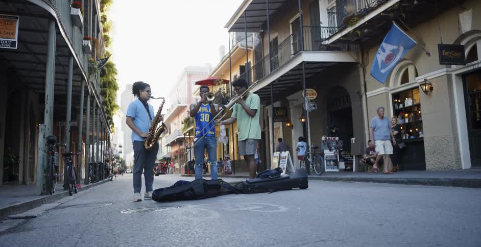 Three young boys play music in the middle of the road