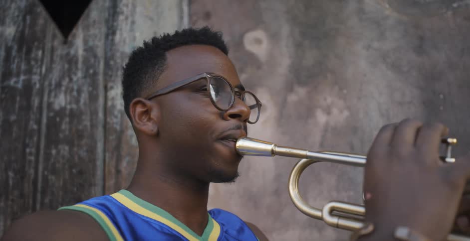 A young black man plays a musical instrument