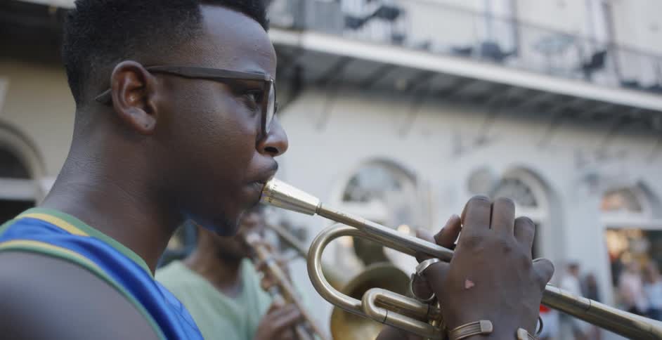 Two black boys wearing glasses play saxophone in the square by day