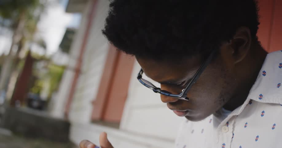 Young man writing pushes up glasses and looks up