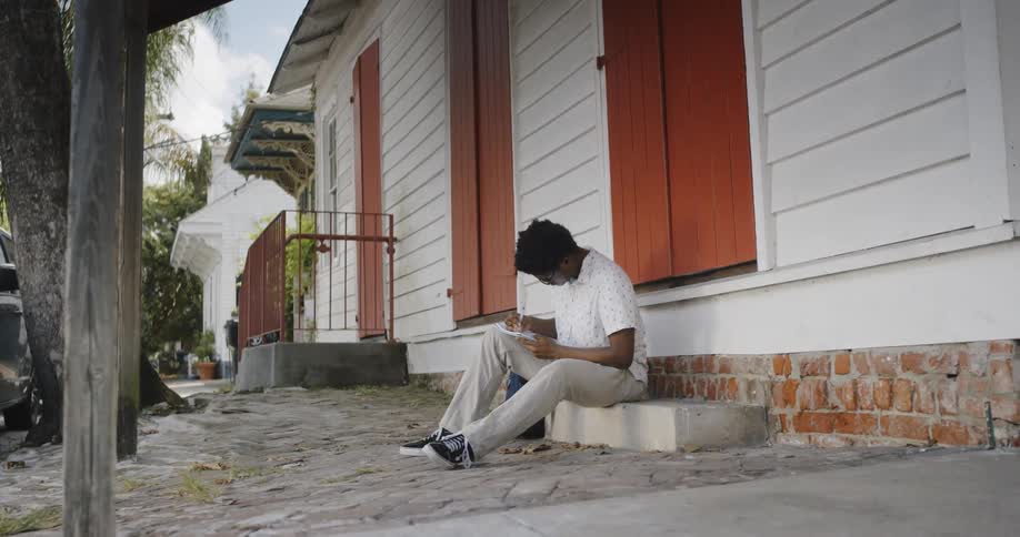 Young man sitting on step outside a house