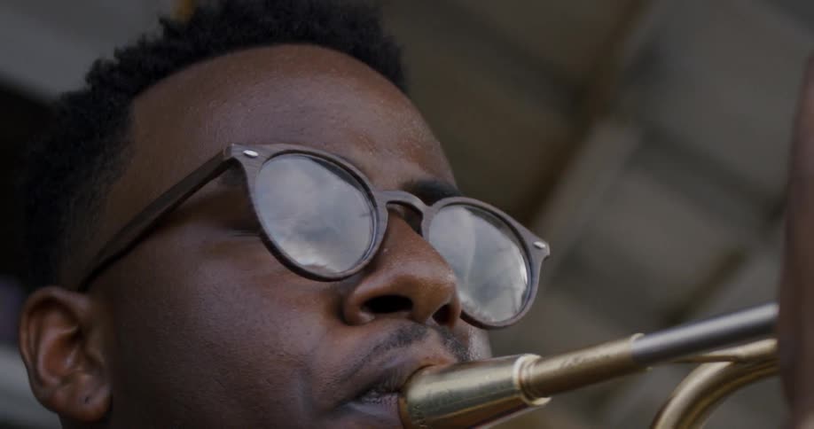 A man glances down while playing a trumpet