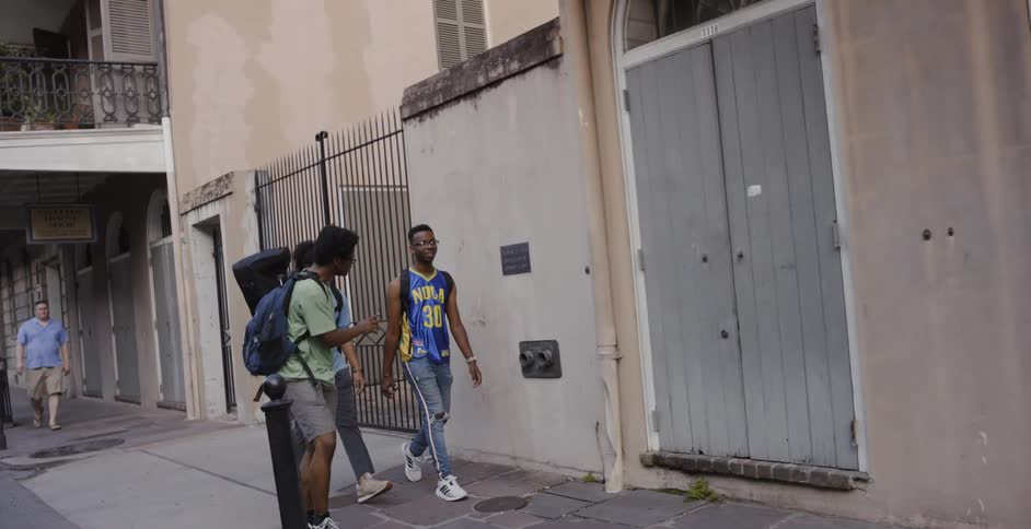 Three friends walk down a sidewalk together