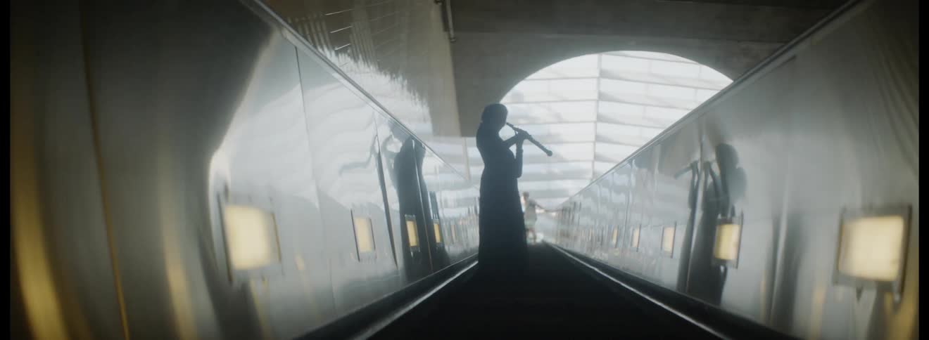 Woman rides escalator while playing musical instrument