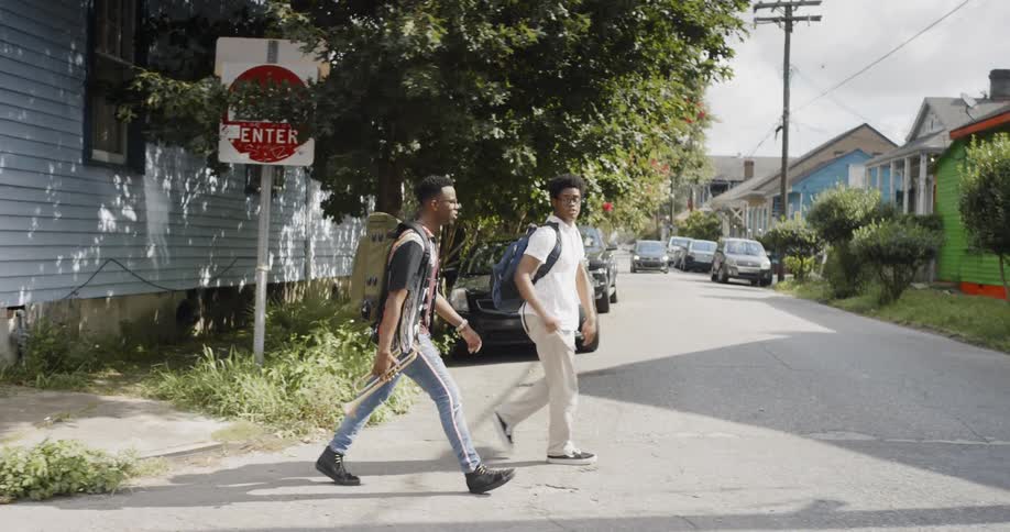 Two men walking the streets one with a trumpet in his hand