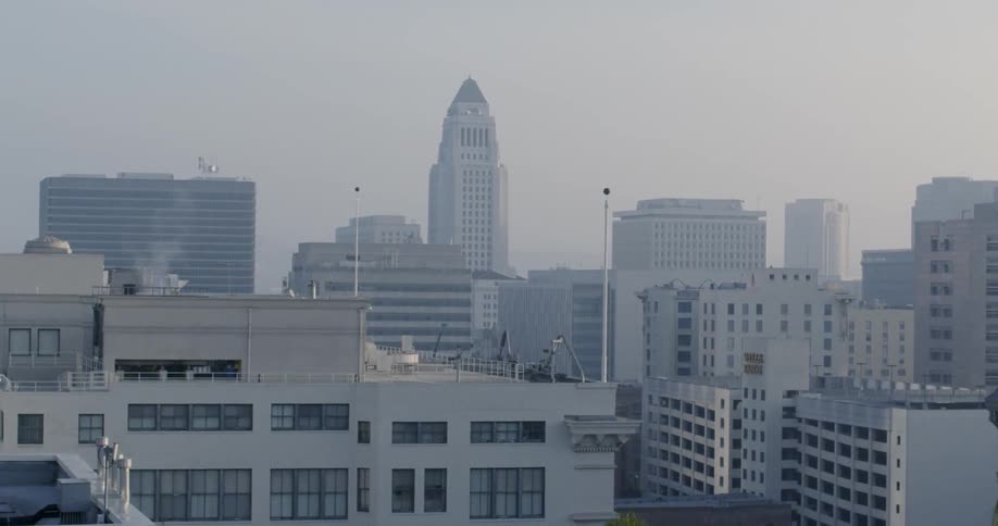 A tall skyscraper looms over other buildings in a city