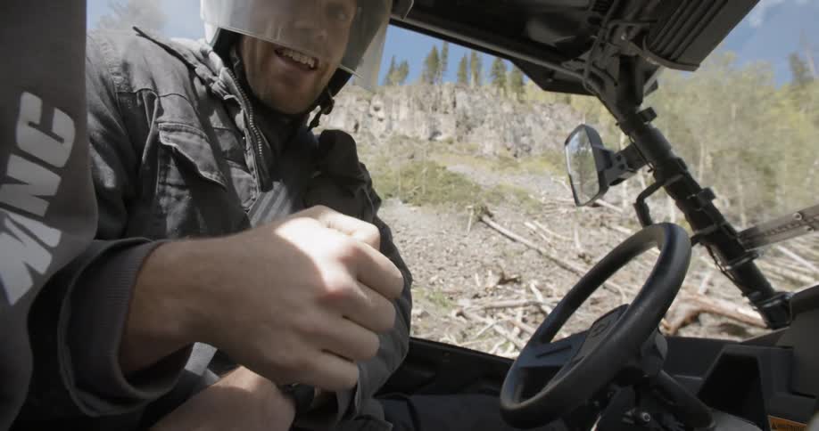 Man with a helmet on his head fastens his seat belt in car on a sunny day