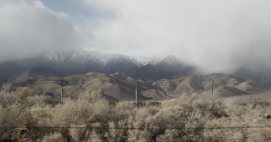 Clouds partially obscure a snowy mountain range