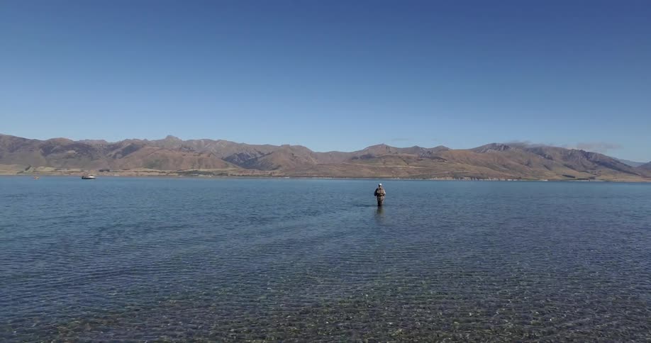 Man fishing while walking hip deep in water