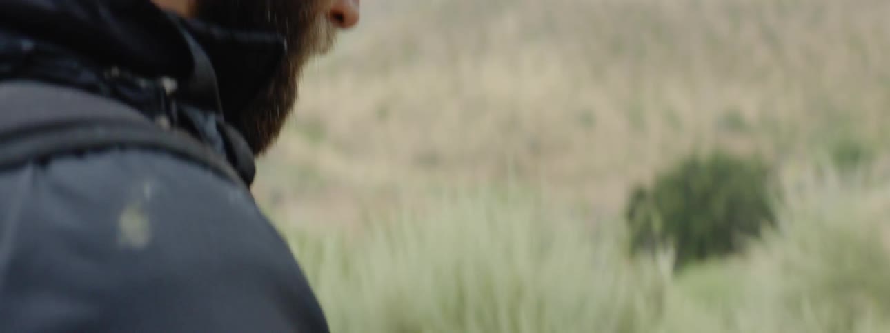 Man stands in field writing in notebook