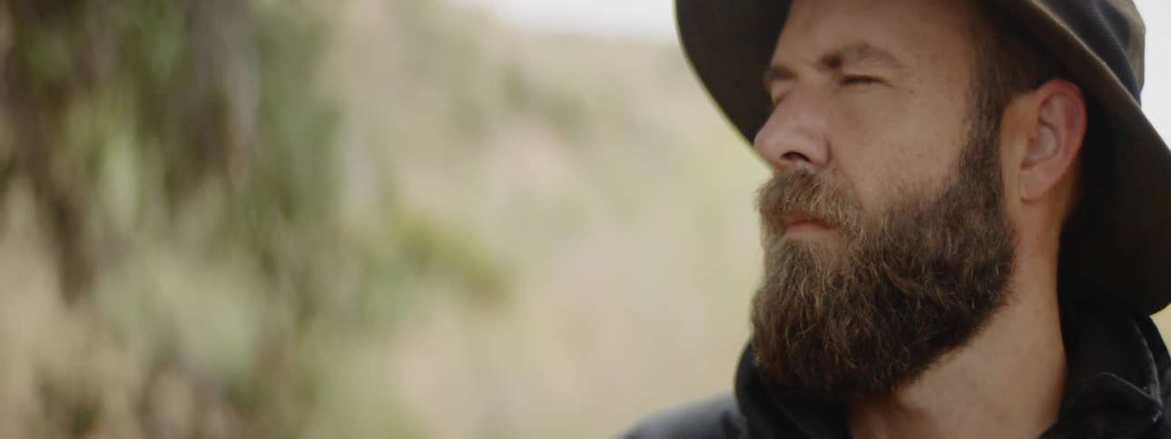 A bearded man squints while painting