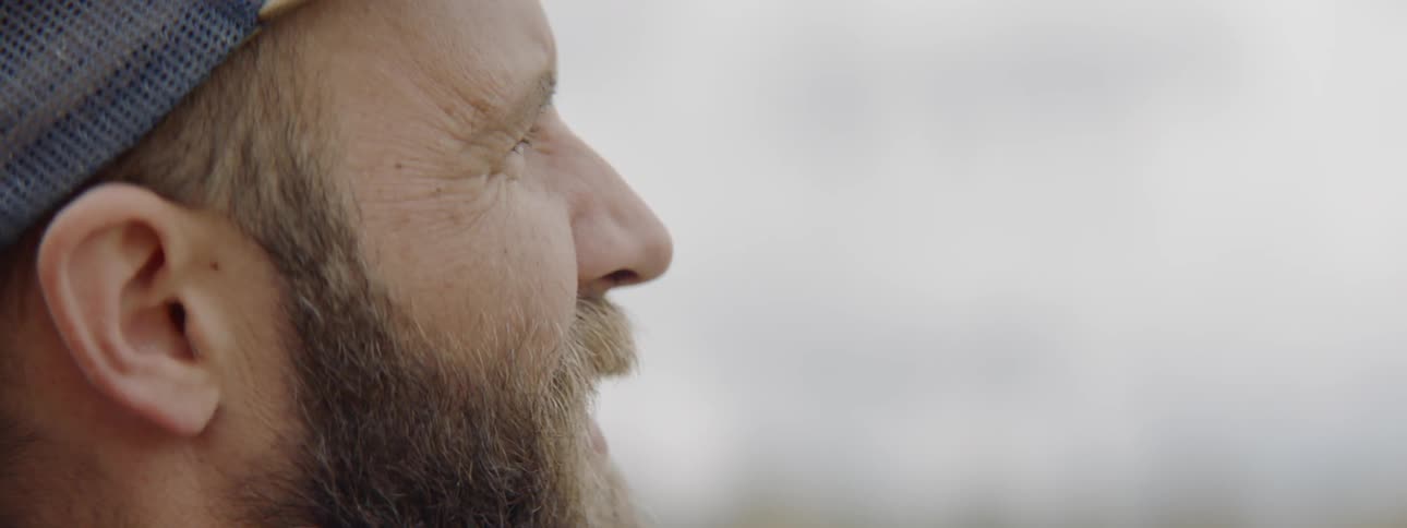 A bearded man squints while staring at something off screen
