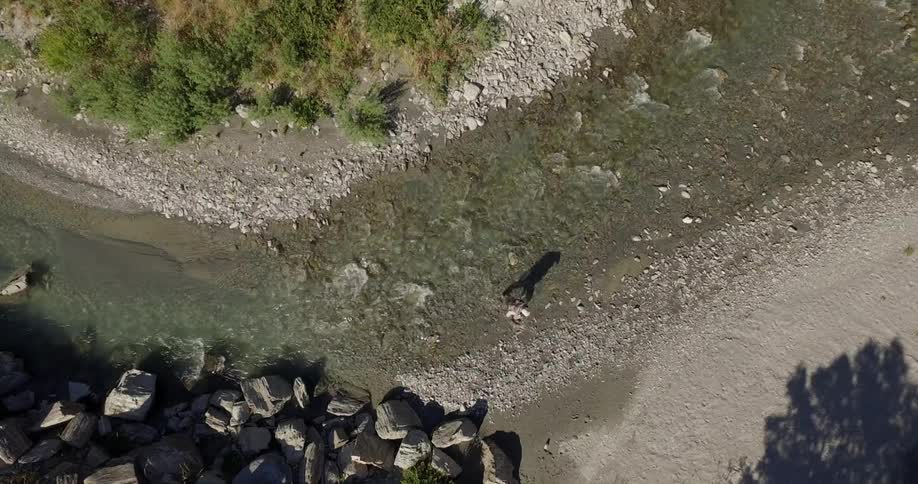 Aerial of a person walking across a stream