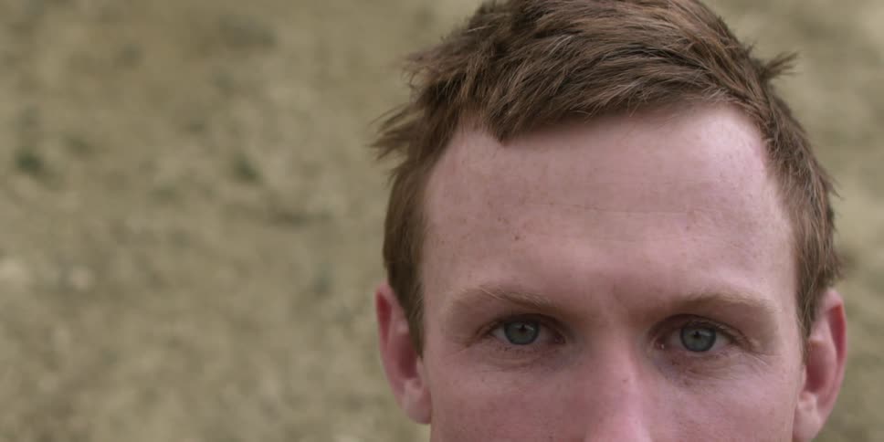 A redheaded man stands staring and blinking