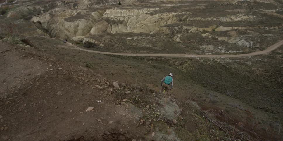 A man performs a bmx backflip trick down a cliffside jump