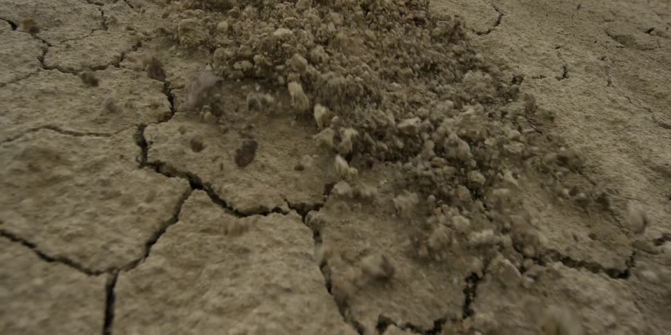 Dirt falling down a dry, cracked ground