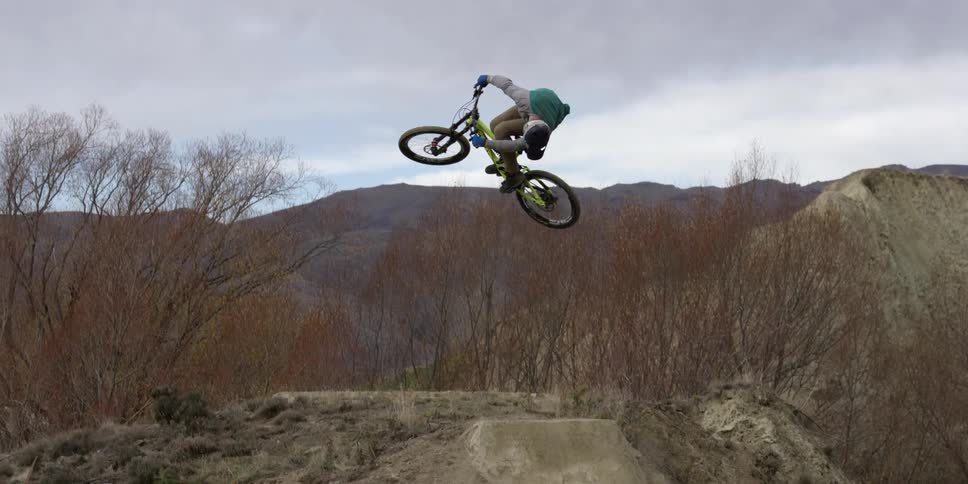 A person rides up a small dirt hill on a bmx bike