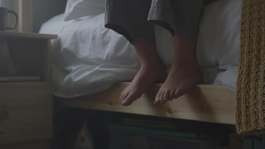 Camera shows someones legs hanging from the bed