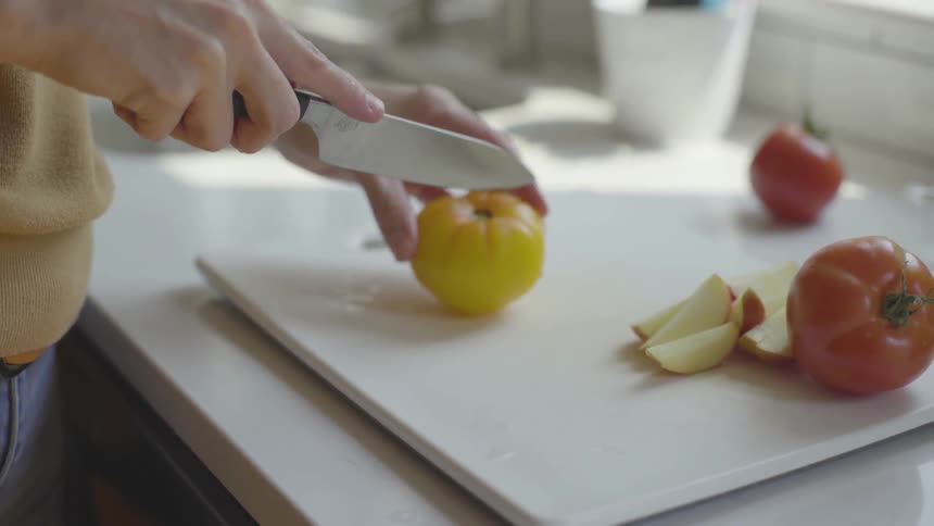 Woman washing and then cutting tomatoes on a kitchen