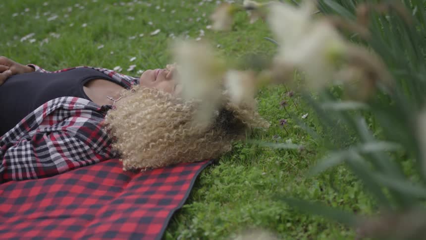 A young woman lies on a blanket on the grass