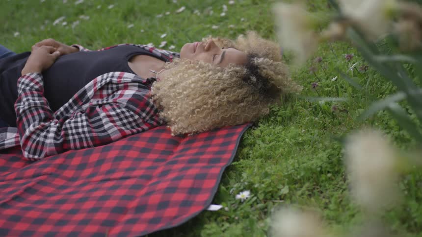 Black woman lying above a towel in the grass
