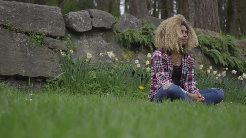 A woman is sitting in the grass outdoors