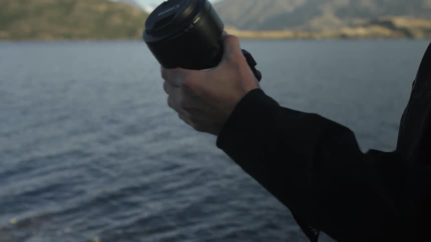 Photographer pulls out his camera and places the strap on