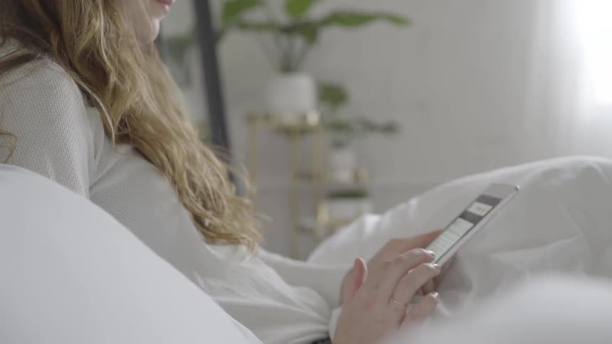 Woman sitting in bed reading on her smartphone