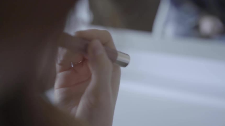 Woman applies lipstick to her lips