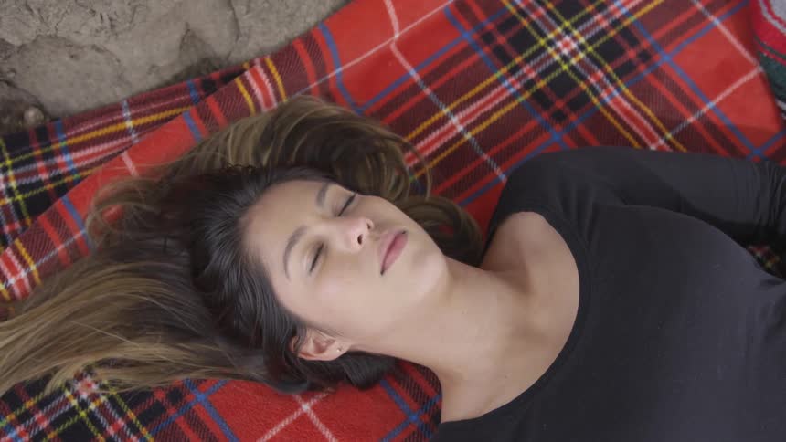 Woman who lies down on blanket opens eyes outdoors during daylight