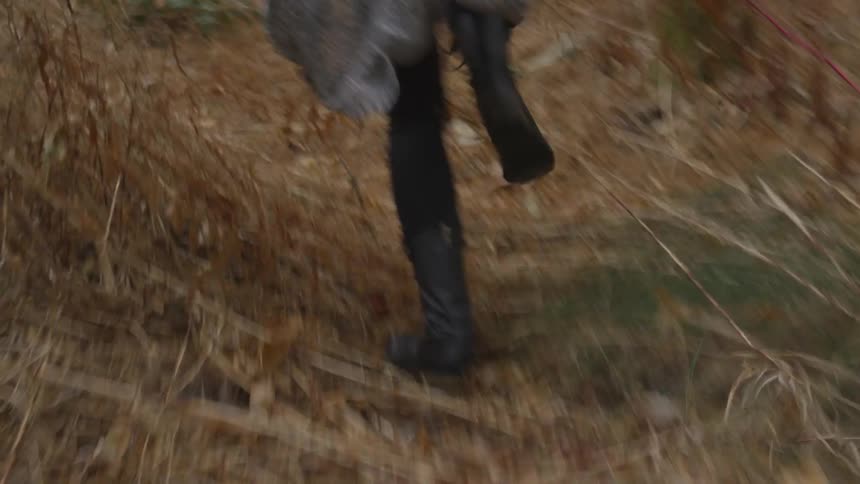 A woman with black boots running in the wilderness
