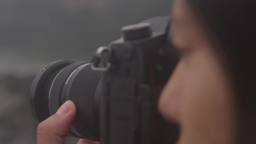 Woman looks through lens of dslr camera