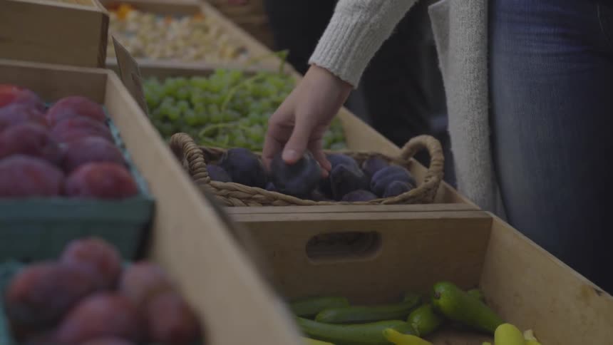 A woman picking up some fruit at a store