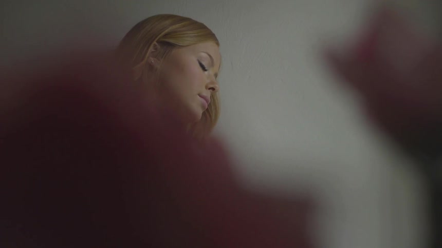 A woman with her arms crossed leans her head against a wall