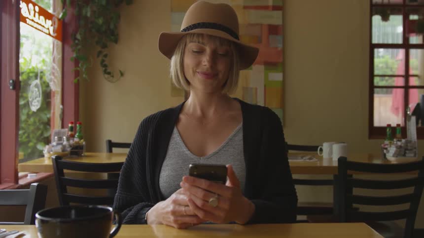 White woman using her cell phone at a table inside a restaurant