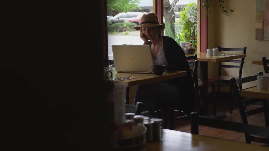 A woman working on a laptop in a coffee shop