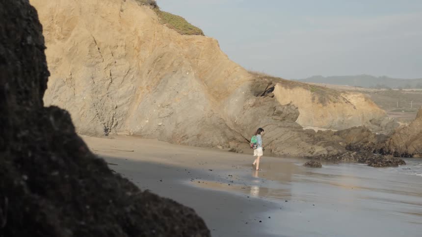 A woman walking through sand at the beach