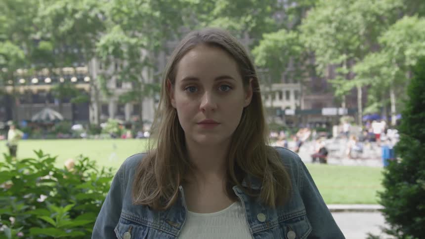 A woman in a park turning to look at the camera