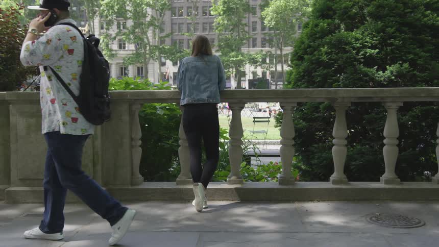 A woman in a denim jacket looking at a building while people are walking by