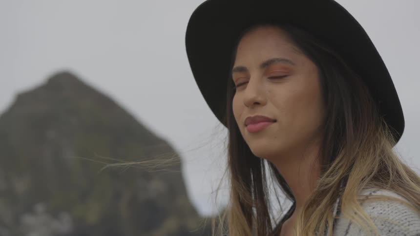 A woman is standing in the wind smiling on a cloudy day