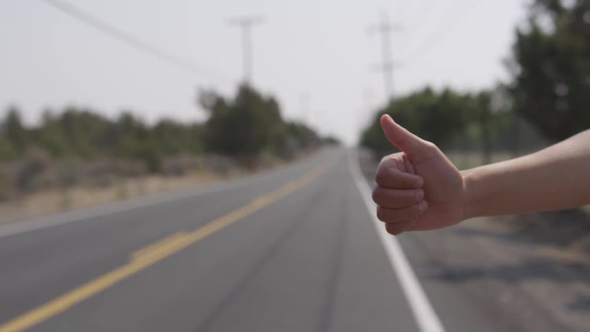 Persons hand with their thumb up hitchhiking