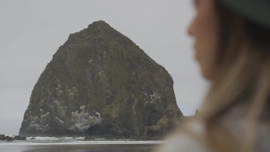 A woman standing at the edge of the coast staring into the sea